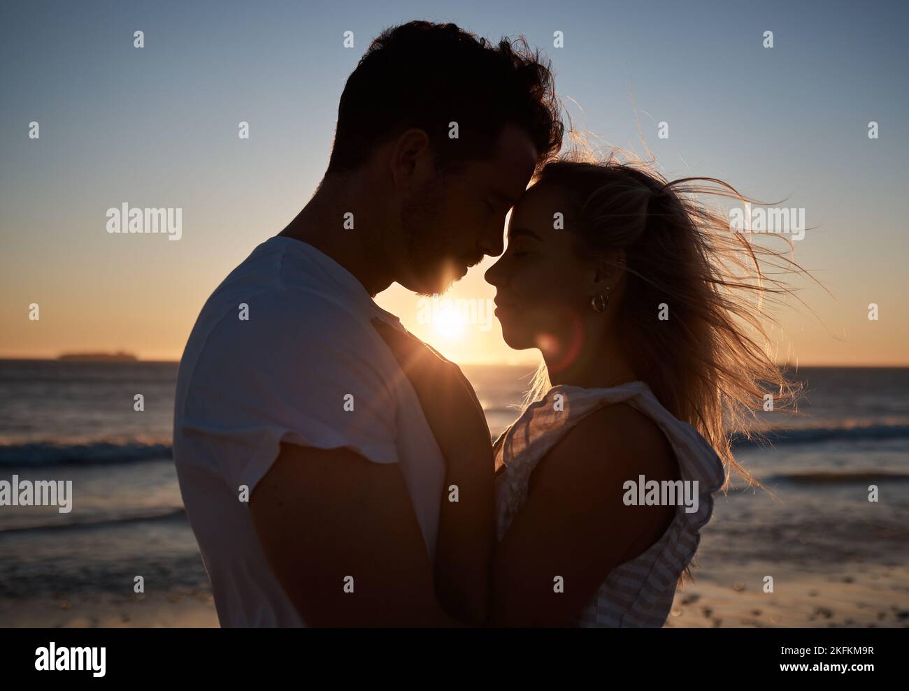 Sonnenuntergang, Silhouette und Paar mit Liebe am Strand, Zuneigung und gute Zeit auf einem Urlaub in Bali. Dunkel, Sonnenaufgang und Mann und Frau mit Sorgfalt, Umarmung Stockfoto
