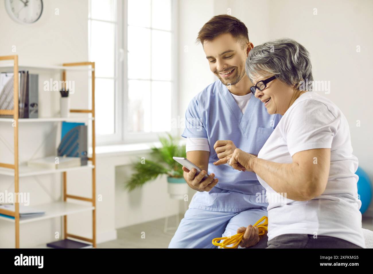 Glückliche Ärztin und ältere Frau, die eine moderne Gesundheitsüberwachungs-App auf einem Mobiltelefon verwendet Stockfoto
