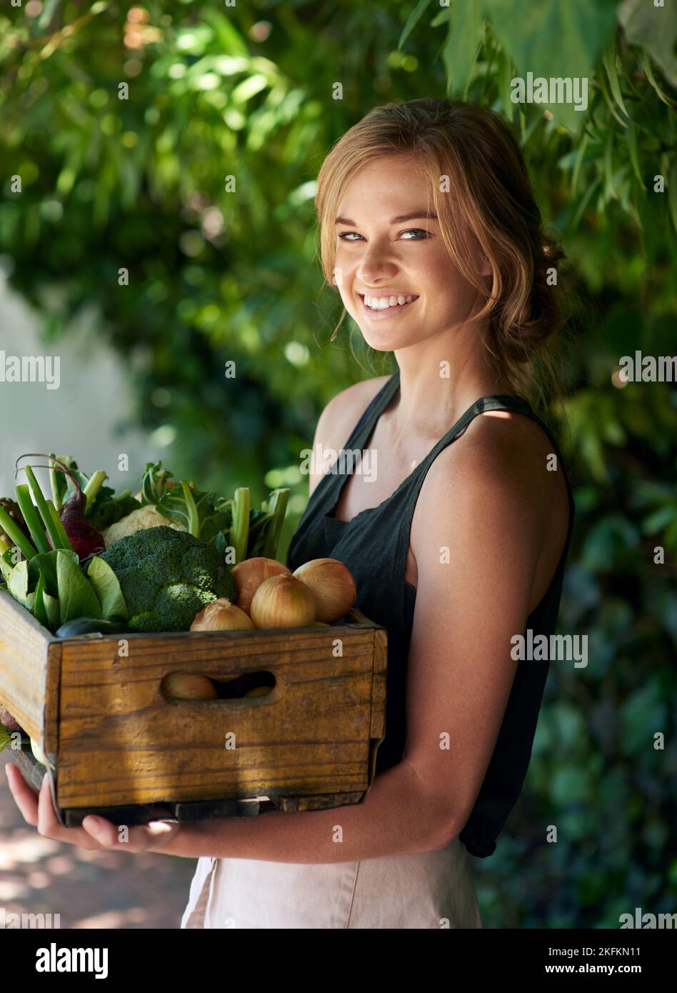 Nichts schmeckt so gut wie hausgemachten Gemüse. Eine junge Frau, die eine Kiste mit Gemüse im Freien hält. Stockfoto