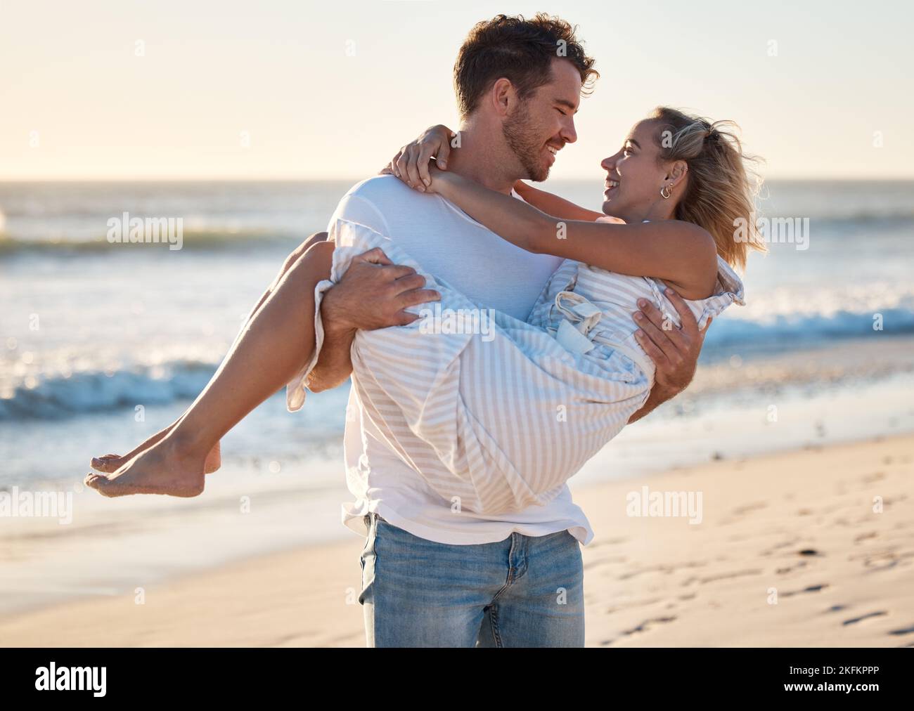 Paar, Strand und Mann tragen Frau für Liebe, Entspannung und Ehe unterstützen zusammen auf Reise Abenteuer oder Urlaub. Freiheit, Vertrauen und glücklicher Mensch Stockfoto