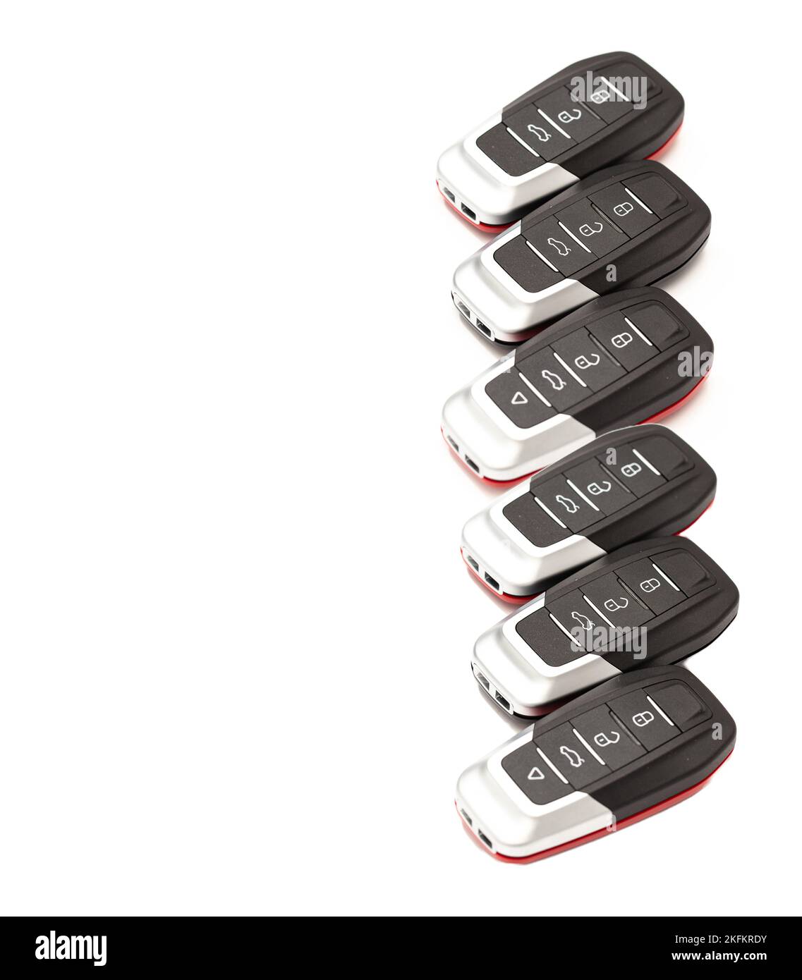 Autoschlüssel liegen in verschiedenen Posen auf weißem Hintergrund. Die schwarzen und roten Schlüssel-Griffstücke der Alarmanlage befinden sich auf weißem Hintergrund. Stockfoto