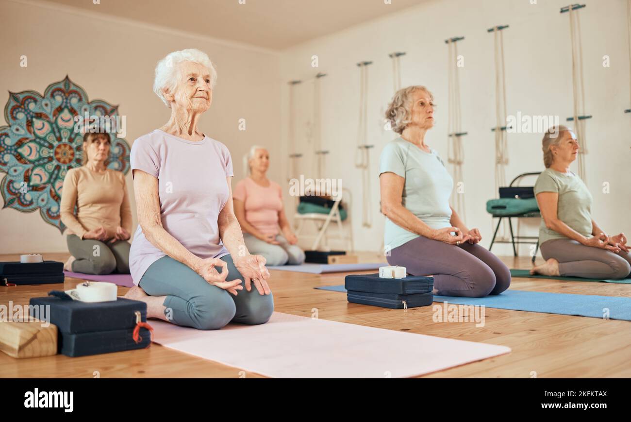 Yoga, Lotus und eine Gruppe älterer Frauen im Fitnessstudio, die für spirituelle Gesundheit und Wellness meditieren. Meditation, Zen-Chakra und pensionierte Frauen trainieren Stockfoto