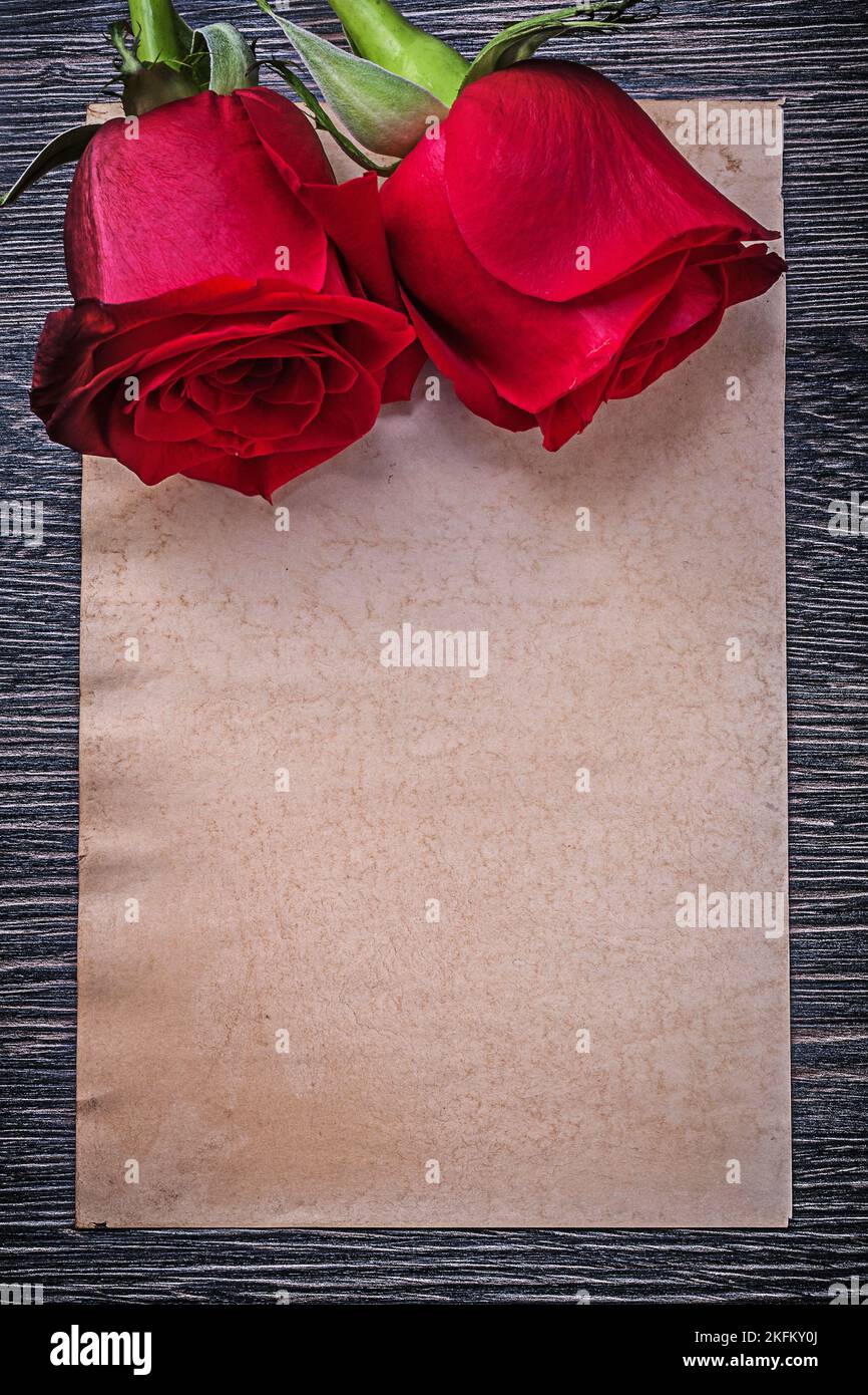 Leeres Vintage-Papier mit roten Duftrosen auf Holzbrett. Stockfoto