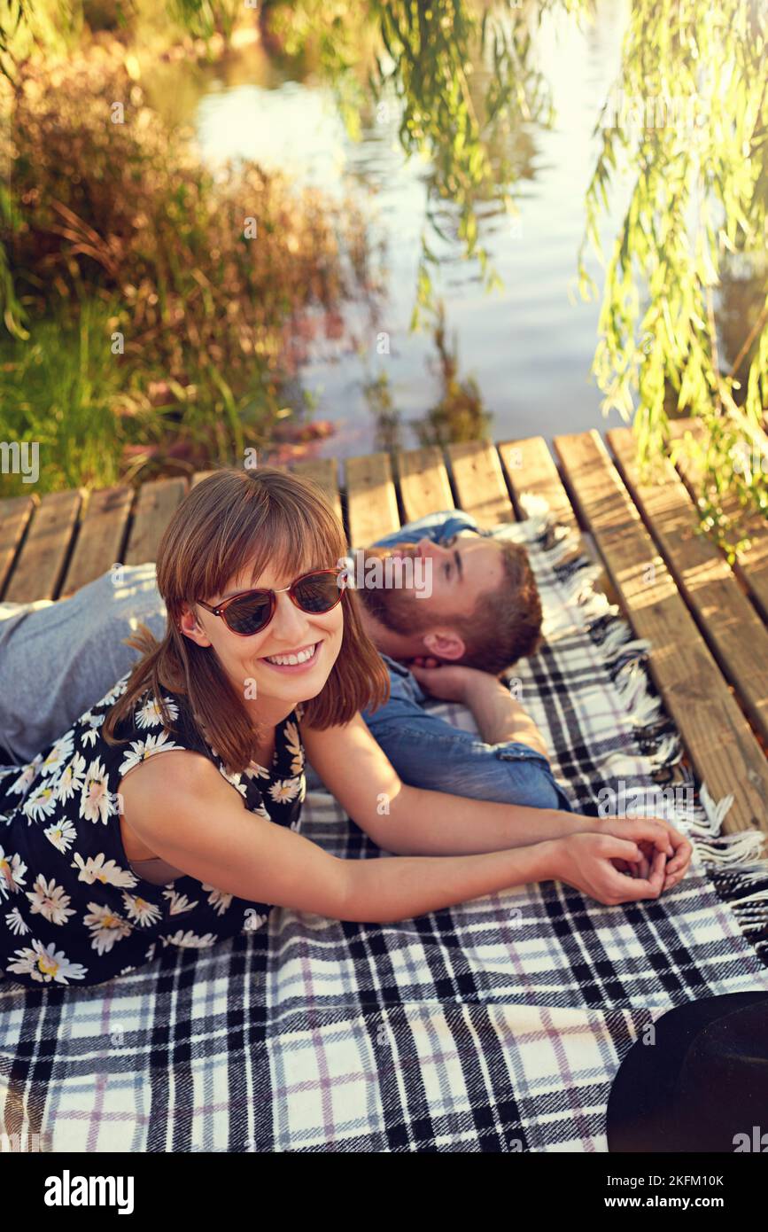 Die beste Art, einen Sommertag zu verbringen. Ein liebevolles junges Paar liegt auf einer Decke im Freien. Stockfoto