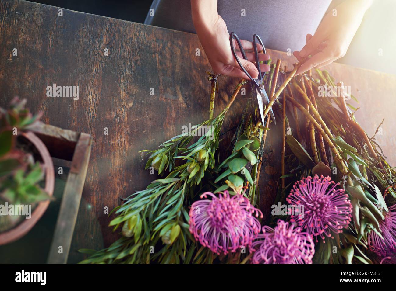 Schaffen Sie eine bunte Welt. Ein hübscher Blumenstrauß wird auf einer Holztheke abgerundet. Stockfoto