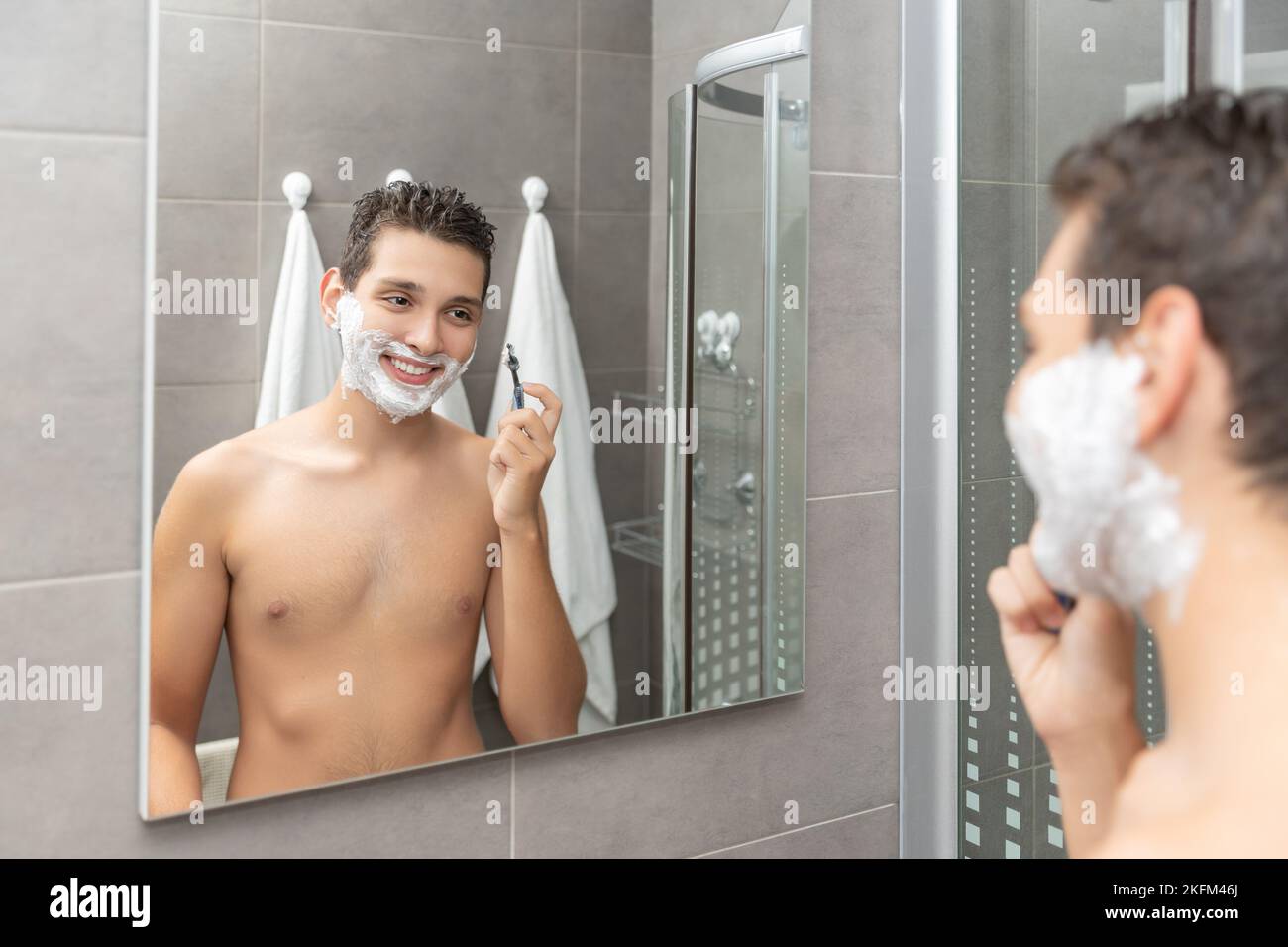 Der junge Mann Rasierprozess im Badezimmer. Der Teenager rasiert den Bart ab. Stockfoto