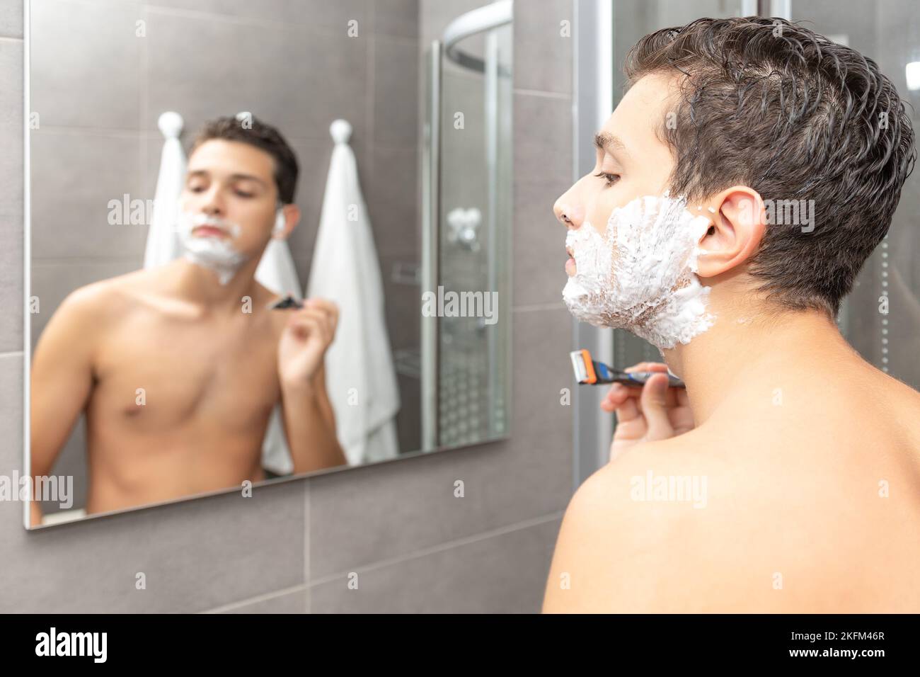 Der junge Mann Rasierprozess im Badezimmer. Der Teenager rasiert den Bart ab. Stockfoto
