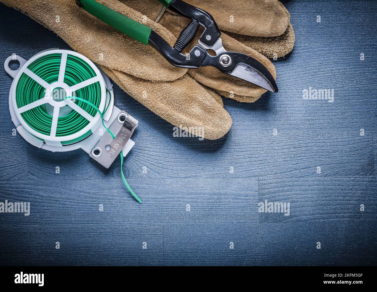 Grüner Gartendraht und Gartenschere am Handschuh. Stockfoto