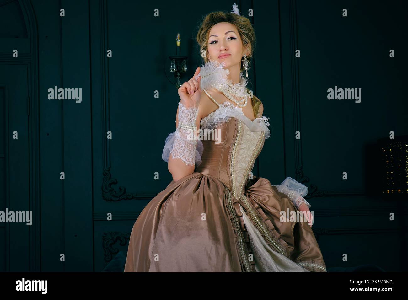Eine junge Frau in einem Kleid und Spitze aus dem 18.. Jahrhundert steht im Boudoir und ist hochtragend und sexuell kokett Stockfoto