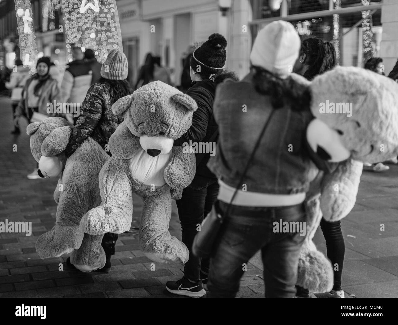 Ein Schwarzweißbild von Touristen mit ihren riesigen Kuschelspielzeugen in Londons Mayfair. Stockfoto