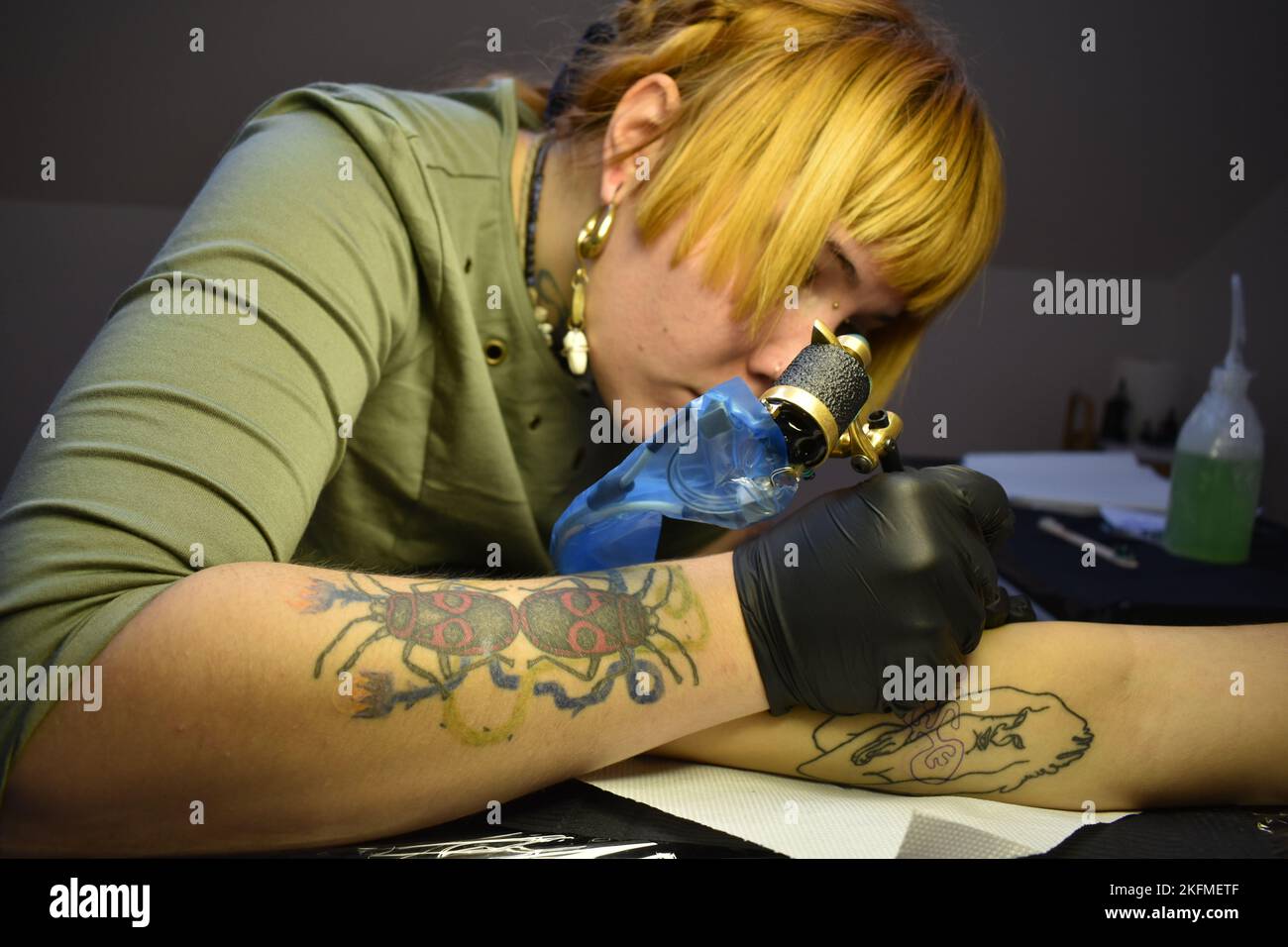 Ein Mädchen, das sich von einem Tattoo-Künstler tätowieren lässt Stockfoto