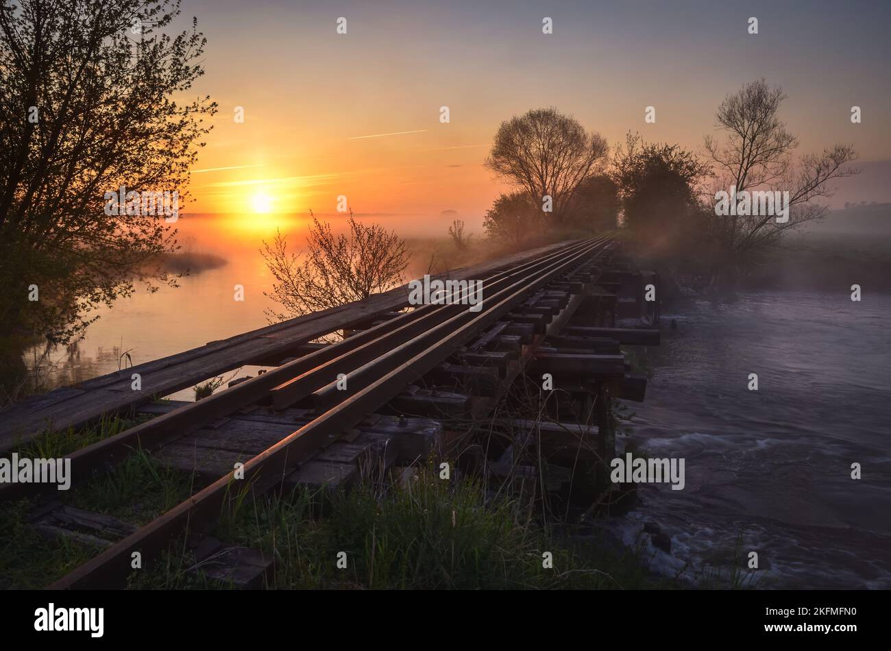 Schöner Sommermorgen. Brücke mit Schienen bei einem schönen Sonnenaufgang. Foto aufgenommen in Motkowice, Polen. Stockfoto
