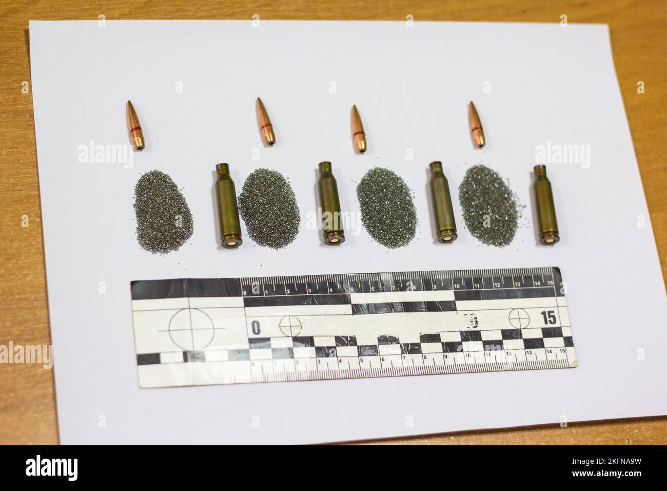 Kugel, Patronenkoffer, Patrone, forensisches Lineal auf einem Blatt weißem Papier. Stockfoto