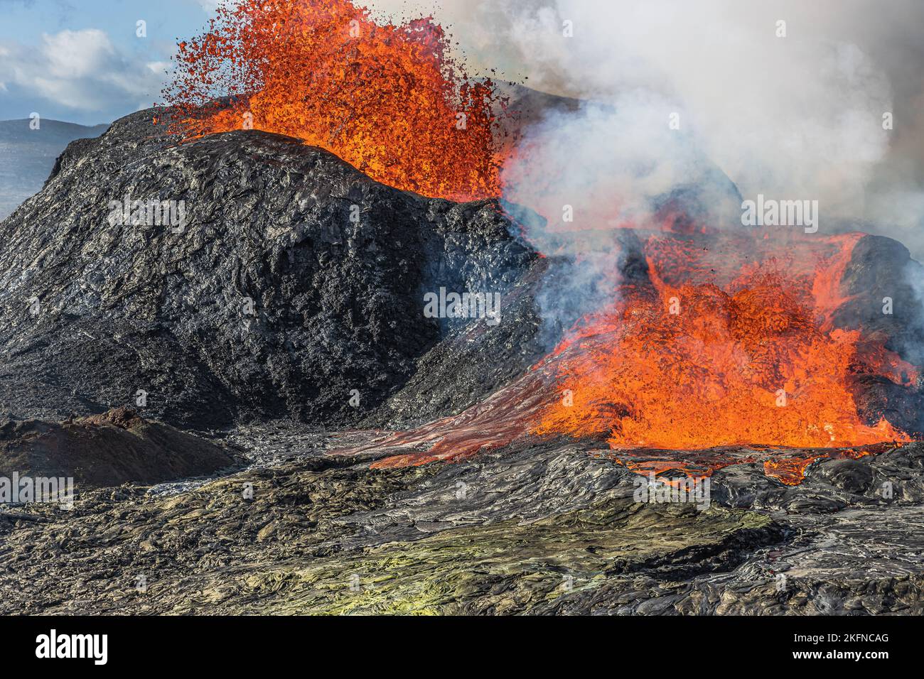 Direkter Blick auf den ausgießenden Vulkan mit Lavafringbrunnen auf Island. Aktiver Vulkan am Tag. Vulkan bricht mit starkem Lavafluss aus. Dunkler Stein Stockfoto