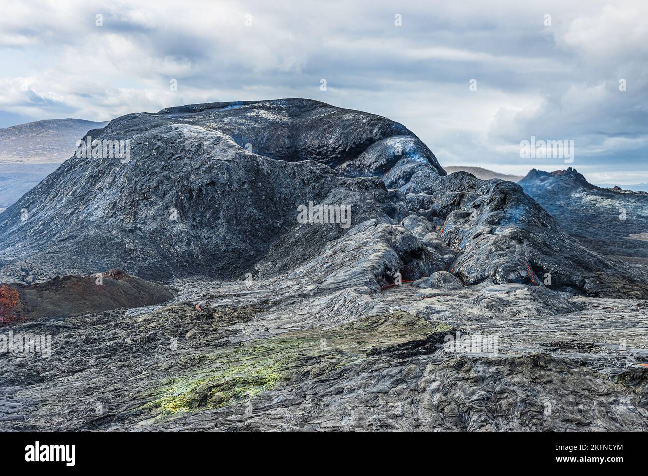 Bewölkter Tag mit Vulkankrater in Island. Landschaft auf der Halbinsel Reykjanes. Krater mit gekühltem Magma. Tageslicht mit bewölktem Himmel. Rötlich, grün Stockfoto