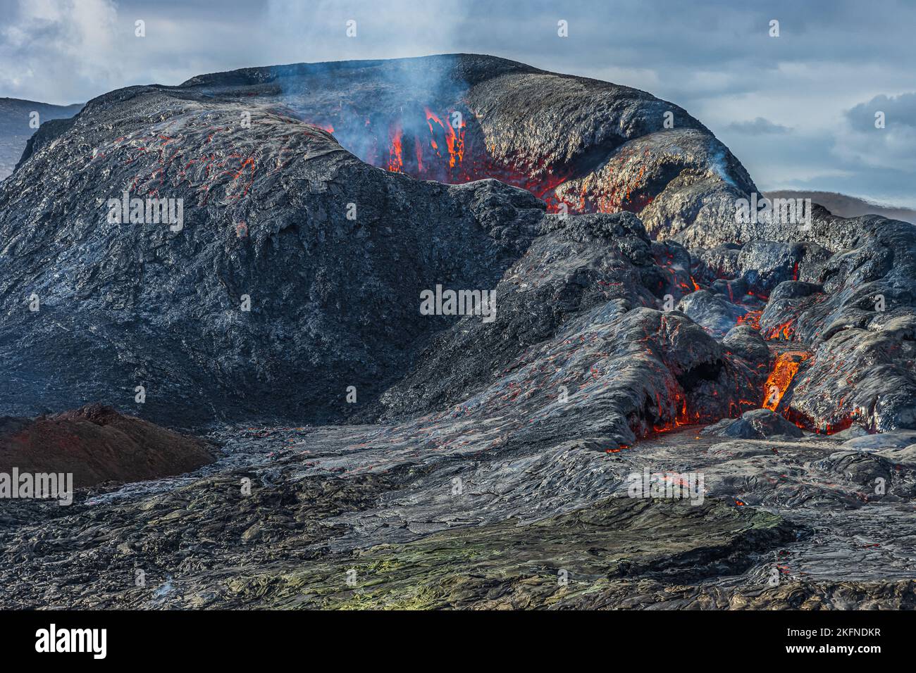 Blick auf den vulkanischen Krater auf der Halbinsel Reykjanes. Vulkanlandschaft in Island. Dampf vom Vulkan. Kleine rote Lava am Rand des Vulkans Stockfoto