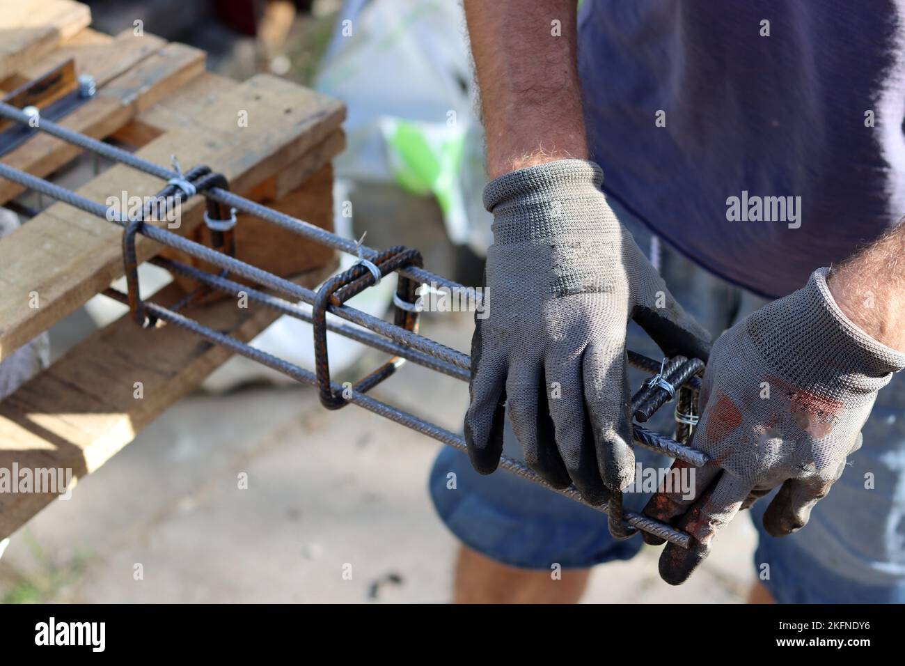 Handgehaltener Verstärkungsstahl. Professioneller Bauarbeiter. Nahaufnahme der Hände des Baumeisters in Schutzhandschuhen. Stockfoto