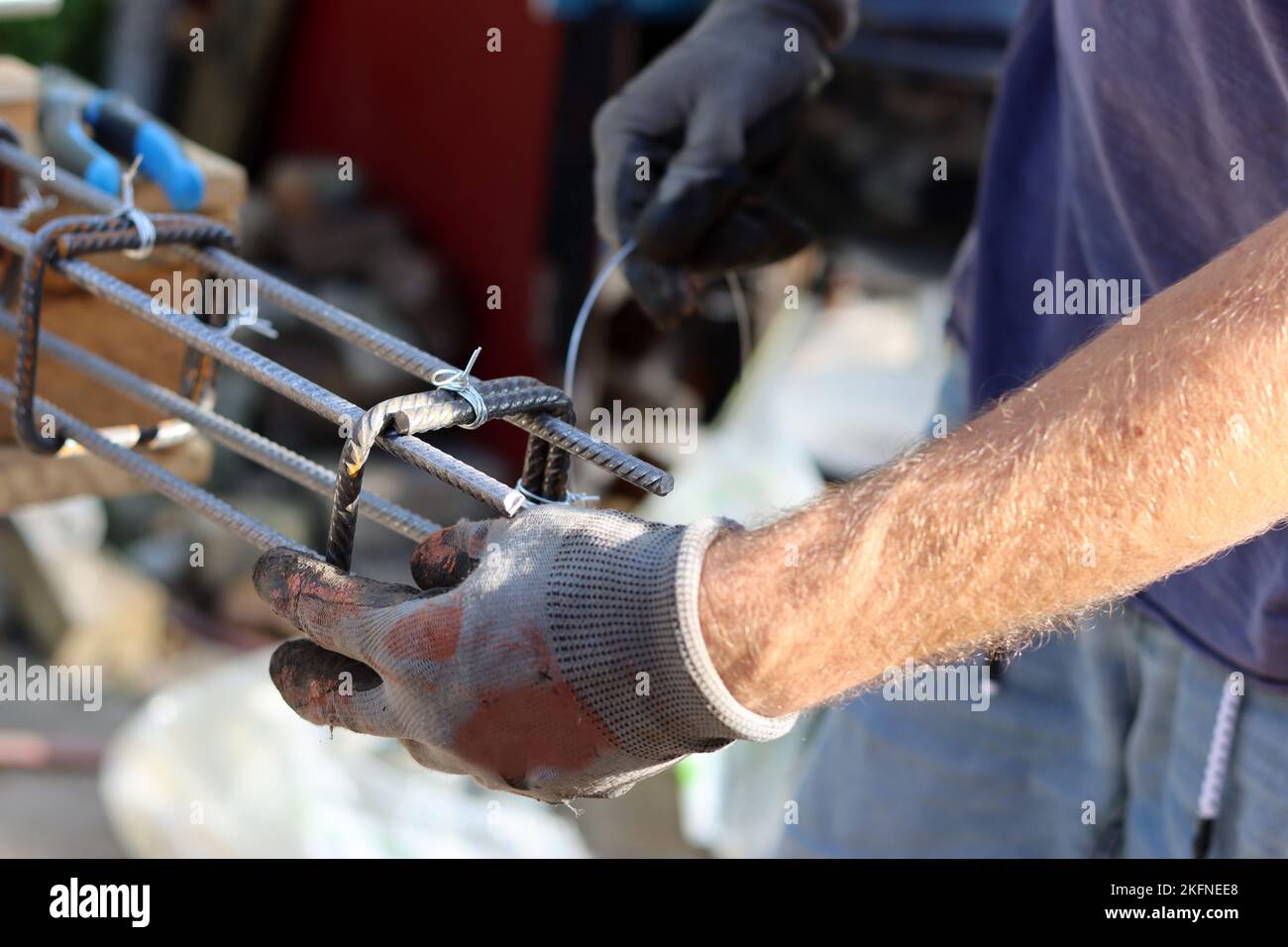 Handgehaltener Verstärkungsstahl. Professioneller Bauarbeiter. Nahaufnahme der Hände des Baumeisters in Schutzhandschuhen. Stockfoto