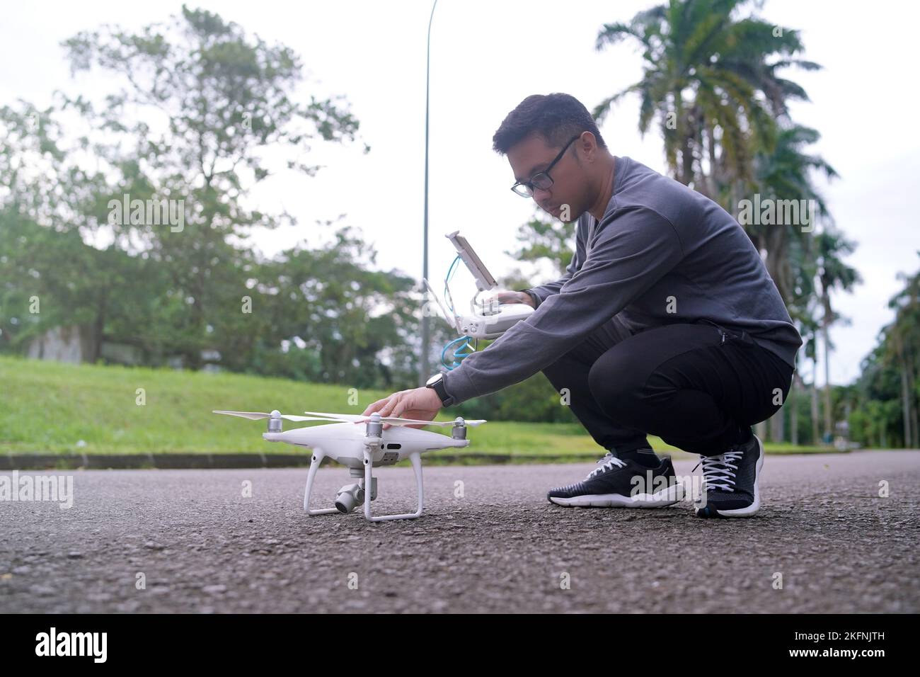 Mitten auf der Straße betreibt ein junger Mann eine Drohne. Junger Mann mit Drohne vor dem Flug. Stockfoto