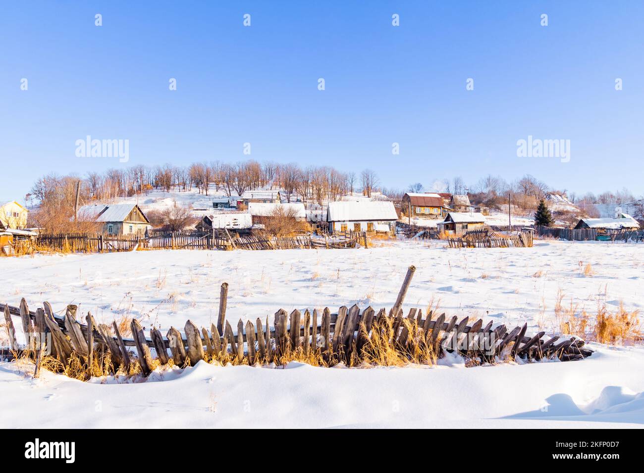 Ein kleines Dorf, ein klappriger Zaun an einem Wintermorgen, bei herrlichem sonnigen Wetter Stockfoto