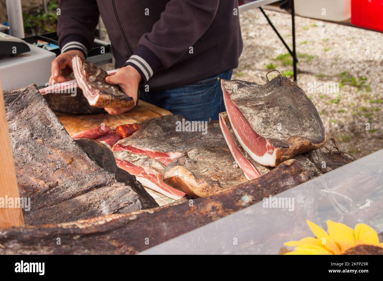 Traditionelles geräuchertes Speck, geschnitten vor Ort während einer Feier im Val di Funes, Dolomiten. Stockfoto