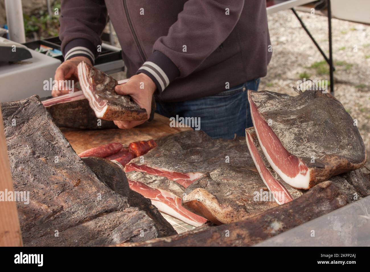 Traditionelles geräuchertes Speck, geschnitten vor Ort während einer Feier im Val di Funes, Dolomiten. Stockfoto