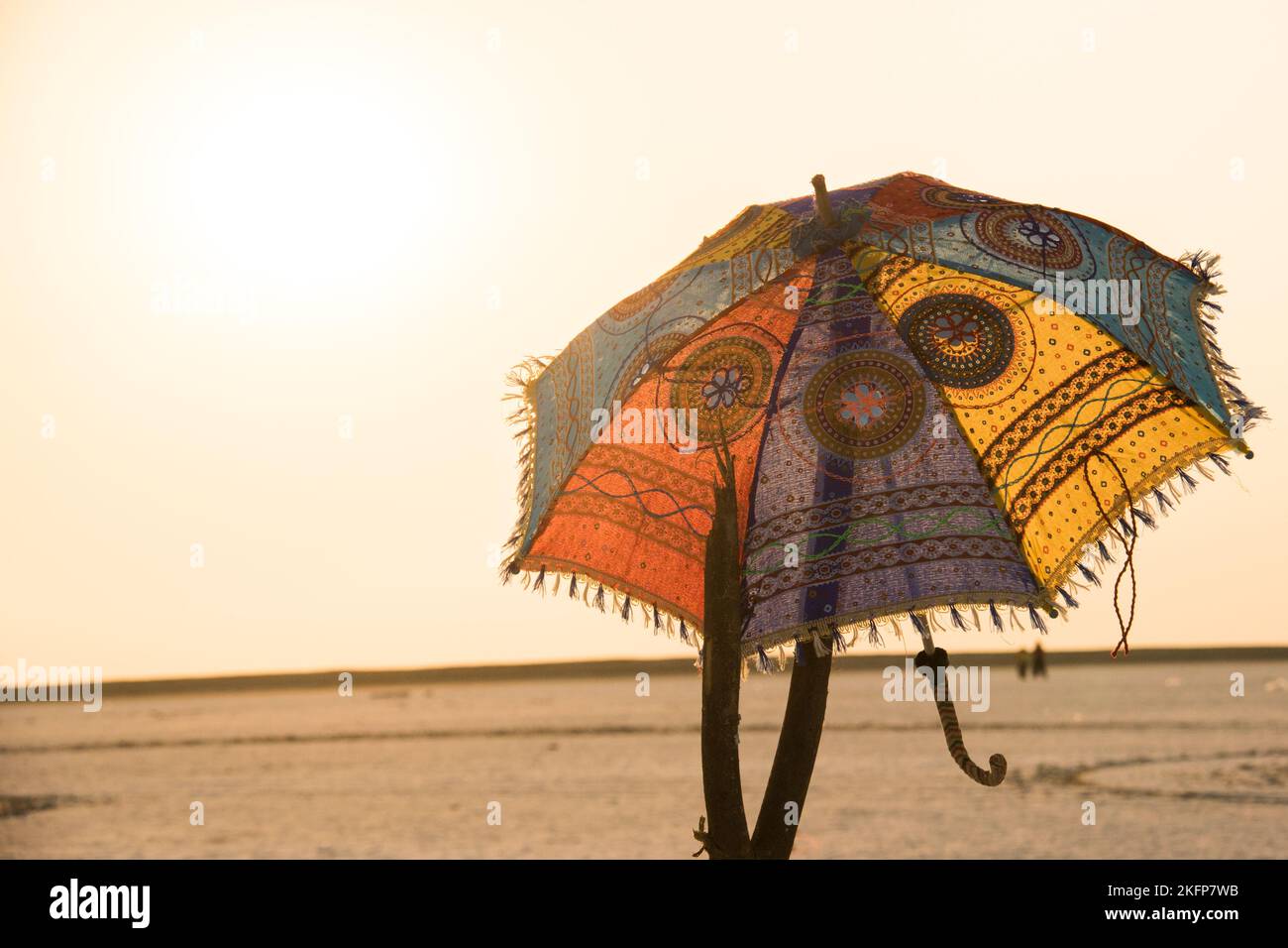 Ein dekorierter Regenschirm mit mehreren Farben und Mustern inmitten der Wüste des Runn von kutch, Gujarat. Stockfoto
