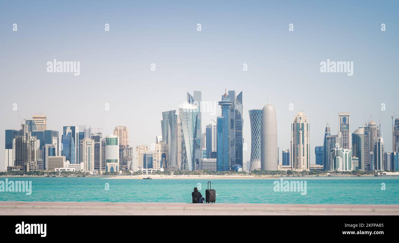 Mann, der vor der Skyline der Stadt in Doha, Katar, sitzt Stockfoto