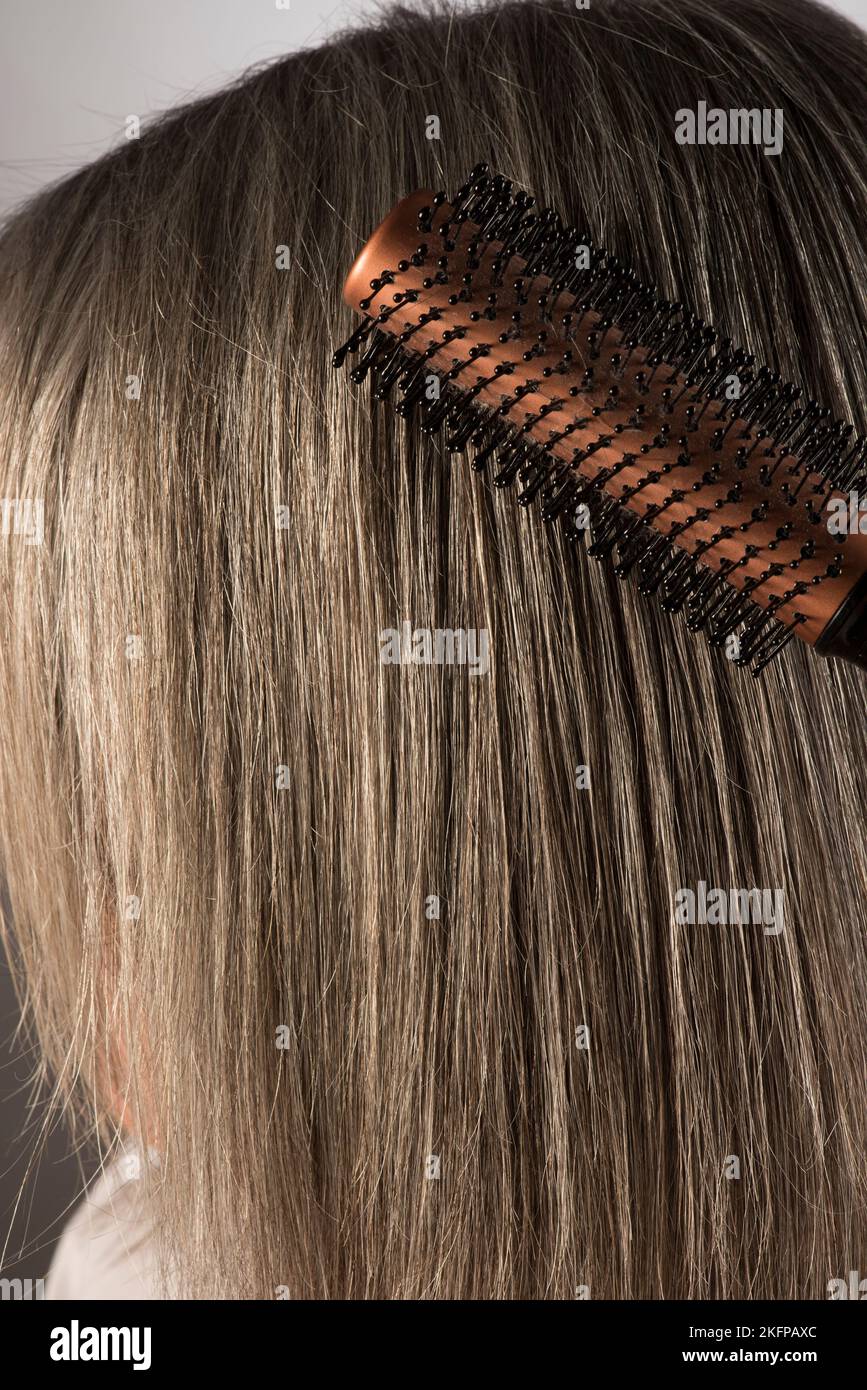 Ein Pinsel wird durch langes graues menschliches Haar geführt. Stockfoto