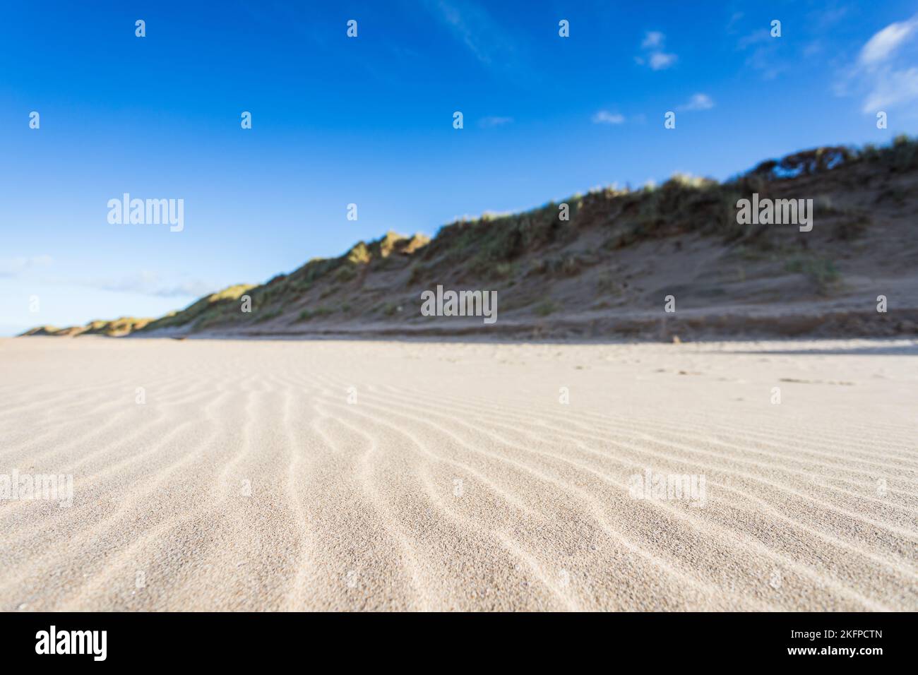Natürliche Wellenmuster im Vordergrund einer Formby-Seestücke mit hohen Sanddünen im Hintergrund. Stockfoto