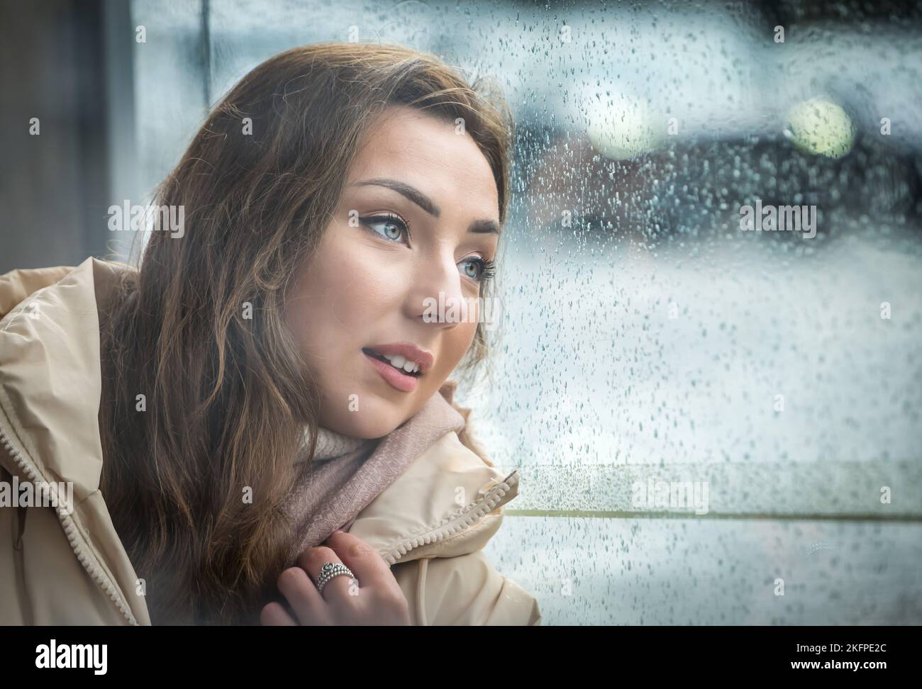 Eine hübsche junge Frau oder ein Model wartet wehmütig an einer Bushaltestelle an einem regnerischen Tag, Edinburgh, Schottland, Großbritannien Stockfoto