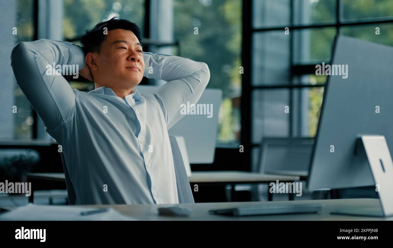Asiatischer koreanischer Senior Geschäftsmann Mitarbeiter allein entspannen Lehnen Sie sich auf Bürostuhl Hände hinter den Kopf legen Komfort Ruhe fühlt sich Zufriedenheit durch Computerarbeit Stockfoto