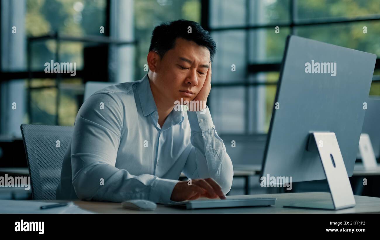 Gelangweilt faul asiatisch Arbeiter Geschäftsmann koreanisch japanisch Mann erschöpft müde männlich sitzen im Büro schlafen müde von langweilig online Arbeit am Computer entwickeln Stockfoto