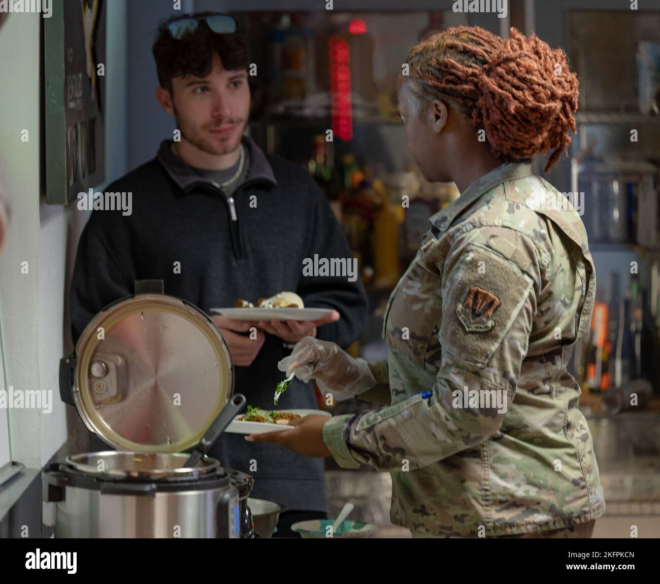 U.S. Air Force Airman 1. Class Jason Cain, 450. Intelligence Squadron, Analyst für alle Quellen, und Staff Sgt. Kyra Stephens, 450., IST Analytikerin von Kampfintelligenzzellen und isst während einer hispanischen Geschichtsfeier auf dem Luftwaffenstützpunkt Ramstein, Deutschland, am 30. September 2022, Essen. Jedes Jahr begehen die Vereinigten Staaten den National Hispanic Heritage Month vom 15. September bis zum 15. Oktober und feiern die Geschichte, Kultur und Beiträge der Amerikaner, deren Vorfahren aus Spanien, Mexiko, der Karibik sowie Mittel- und Südamerika kamen. Stockfoto