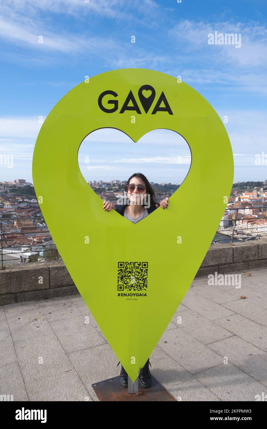 Junge Frau, die auf dem Touristenschild von Vila Nova de Gaia in Portugal posiert Stockfoto