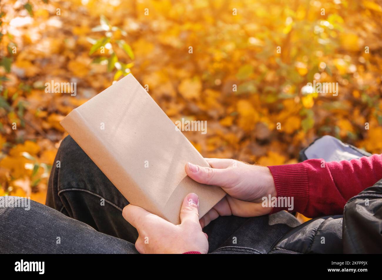 Ein Mann hält ein Buch mit leerem Raum in der herbstlichen Natur. Platz für Buchkopien. Das Konzept des Lesens von Büchern in der Natur. Freier Raum für Werbung. Stockfoto