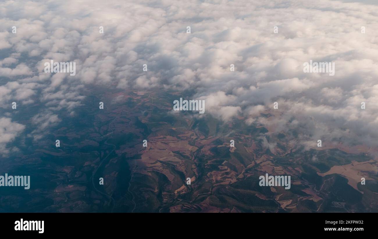 Weiße Wolkenlandschaft mit Blick durch braune und grüne Berge in einer spanischen Landschaft Stockfoto