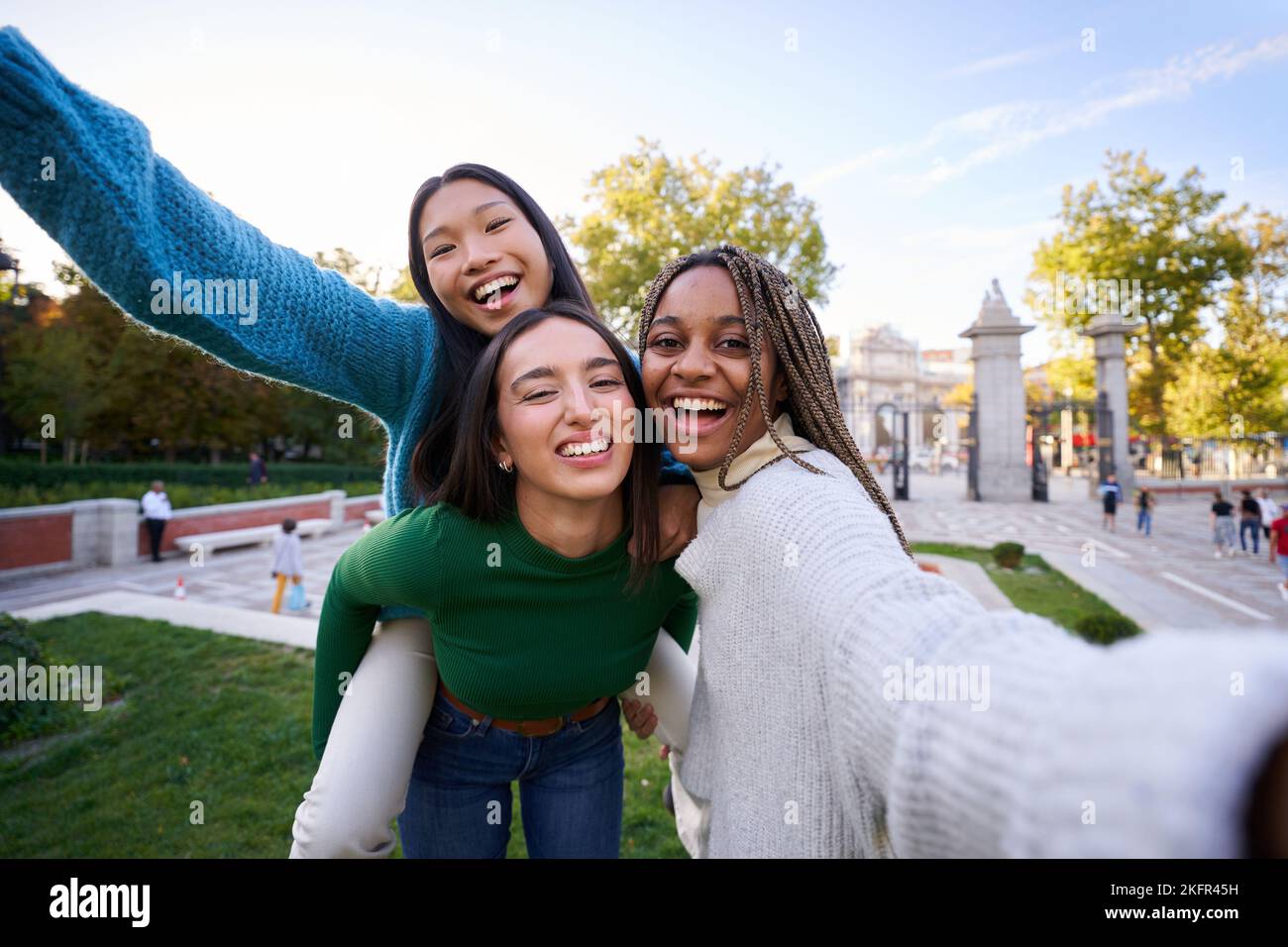 Fröhliches Foto von drei verschiedenen Freundinnen, die ein fröhliches Selfie beim Huckepack machen. Mädchen, die Spaß haben Stockfoto