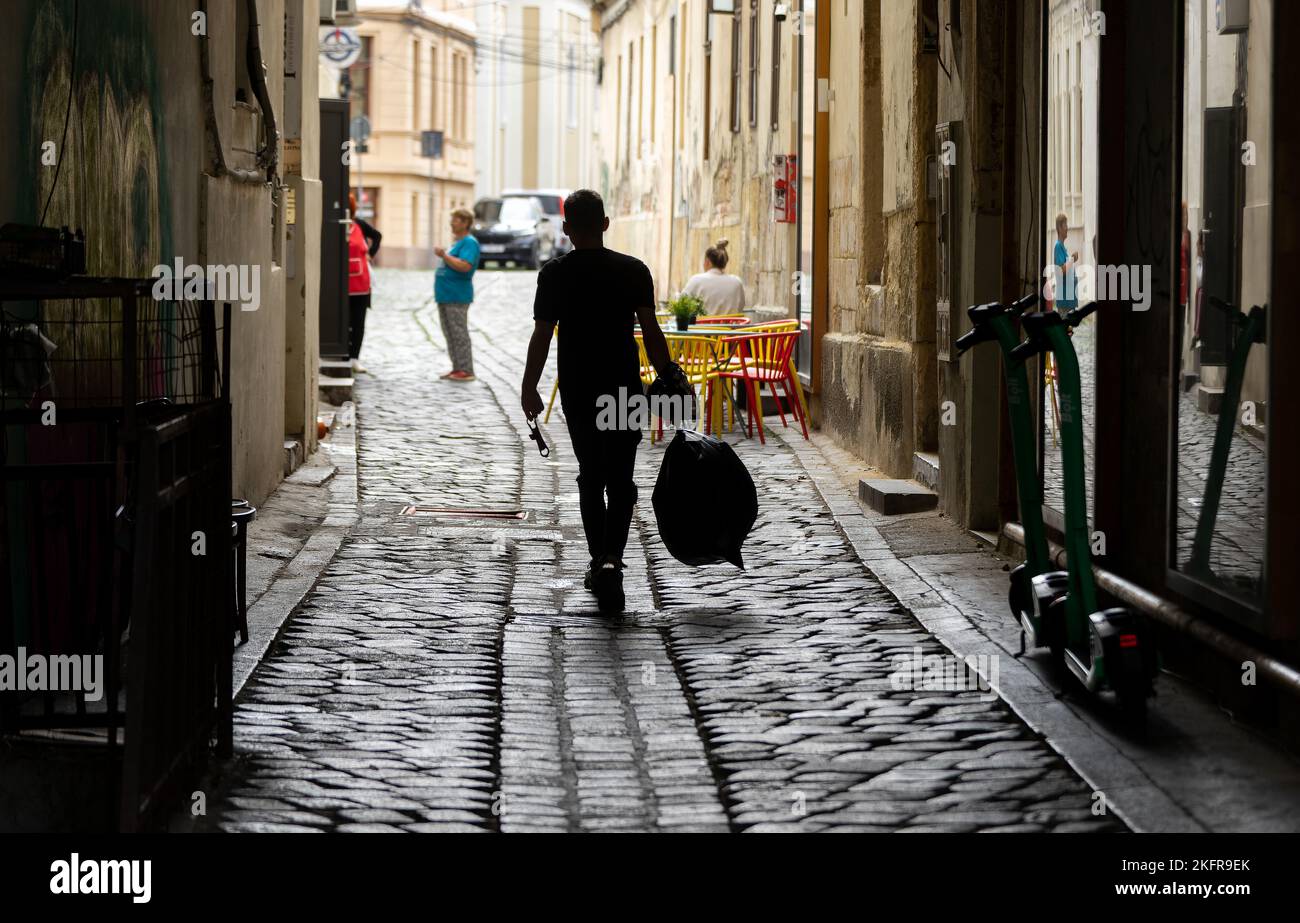 Cluj-Napoca, Rumänien - 17. September 2022: . Ein Angestellter eines Restaurants mit einer schweren Plastiktüte am Union Square, im Zentrum von Cluj-Napoca. Stockfoto
