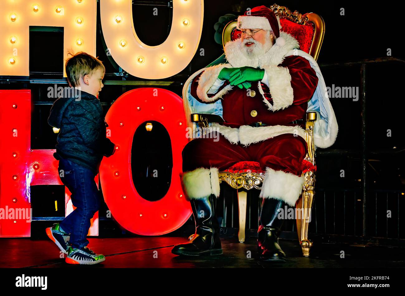 Ein kleiner Junge nähert sich dem Weihnachtsmann während der Weihnachtsbaumbeleuchtung der Stadt im Mardi Gras Park, 18. November 2022, in Mobile, Alabama. Stockfoto