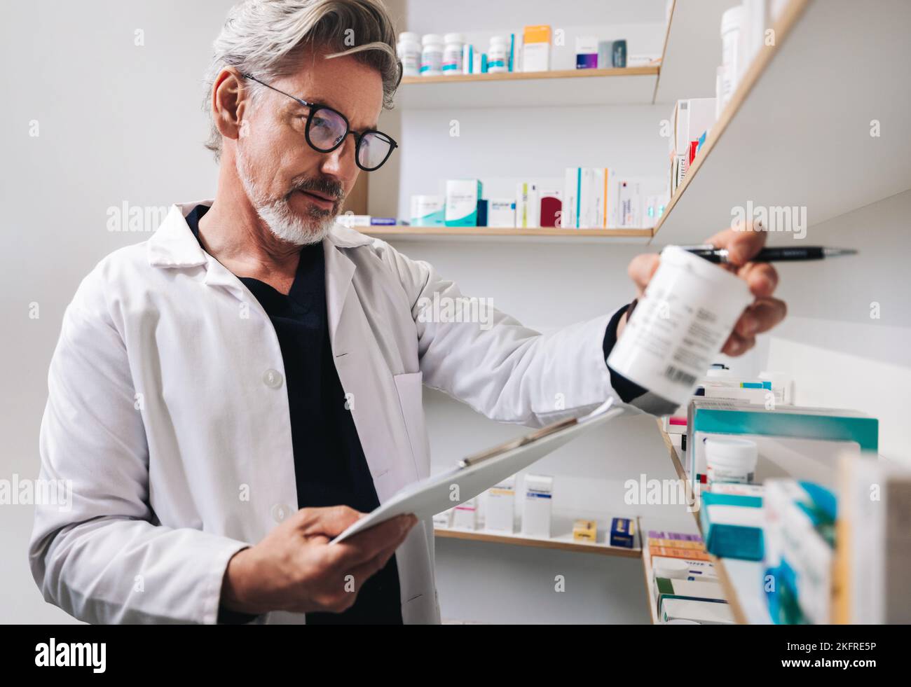 Reifer Apotheker, der ein Medikamentenetikett in einer Drogerie liest. Leitender Mitarbeiter im Gesundheitswesen, der Rezepte in einer Apotheke ausgibt. Stockfoto