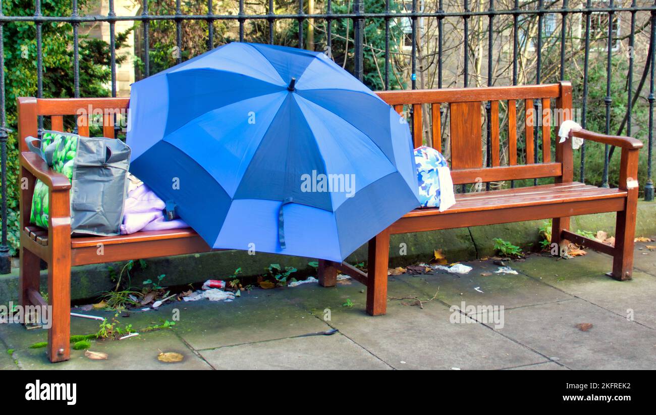 Obdachlose, die auf einer Bank im Regen unter einem Schirm in der Princes Street Edinburgh, Schottland, Großbritannien, schlafen Stockfoto