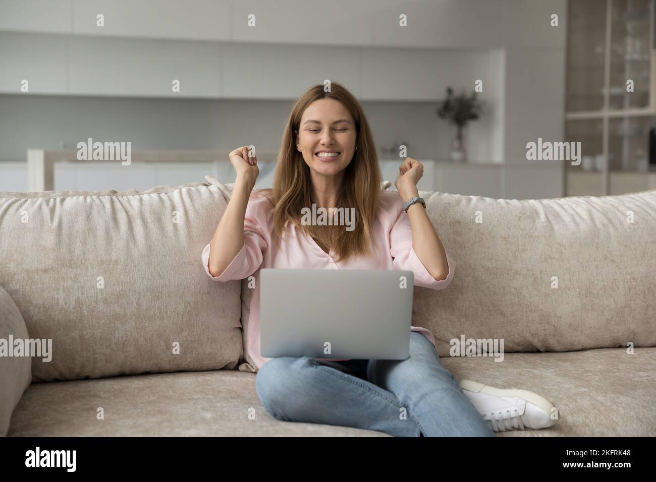 Frau, die auf den Laptop starrt und unglaubliche Nachrichten liest, fühlt sich überglücklich Stockfoto