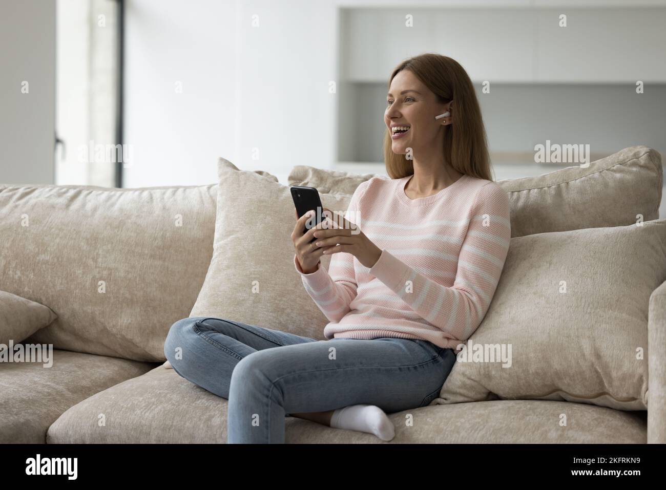 Frau hört mithilfe des Smartphones Sprachnachrichten über Kopfhörer ab Stockfoto
