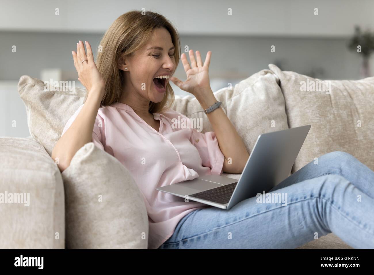 Frau, die auf Laptop starrt, fühlt sich überglücklich, ein großartiges kommerzielles Angebot zu erhalten Stockfoto