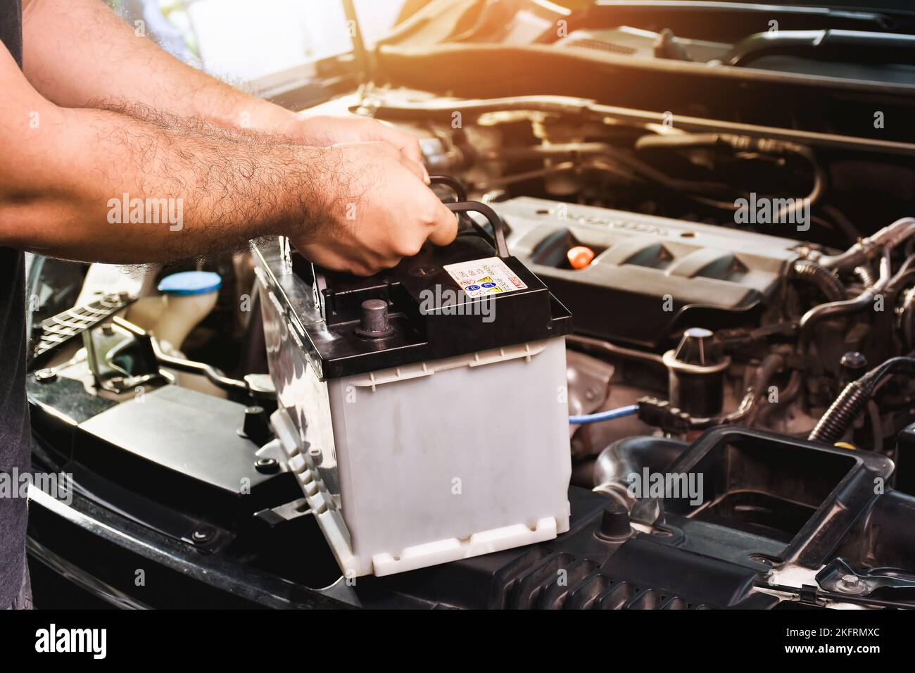 Ein Automechaniker trägt eine Ersatz-Autobatterie für die elektrische Instandhaltung von Autos Stockfoto