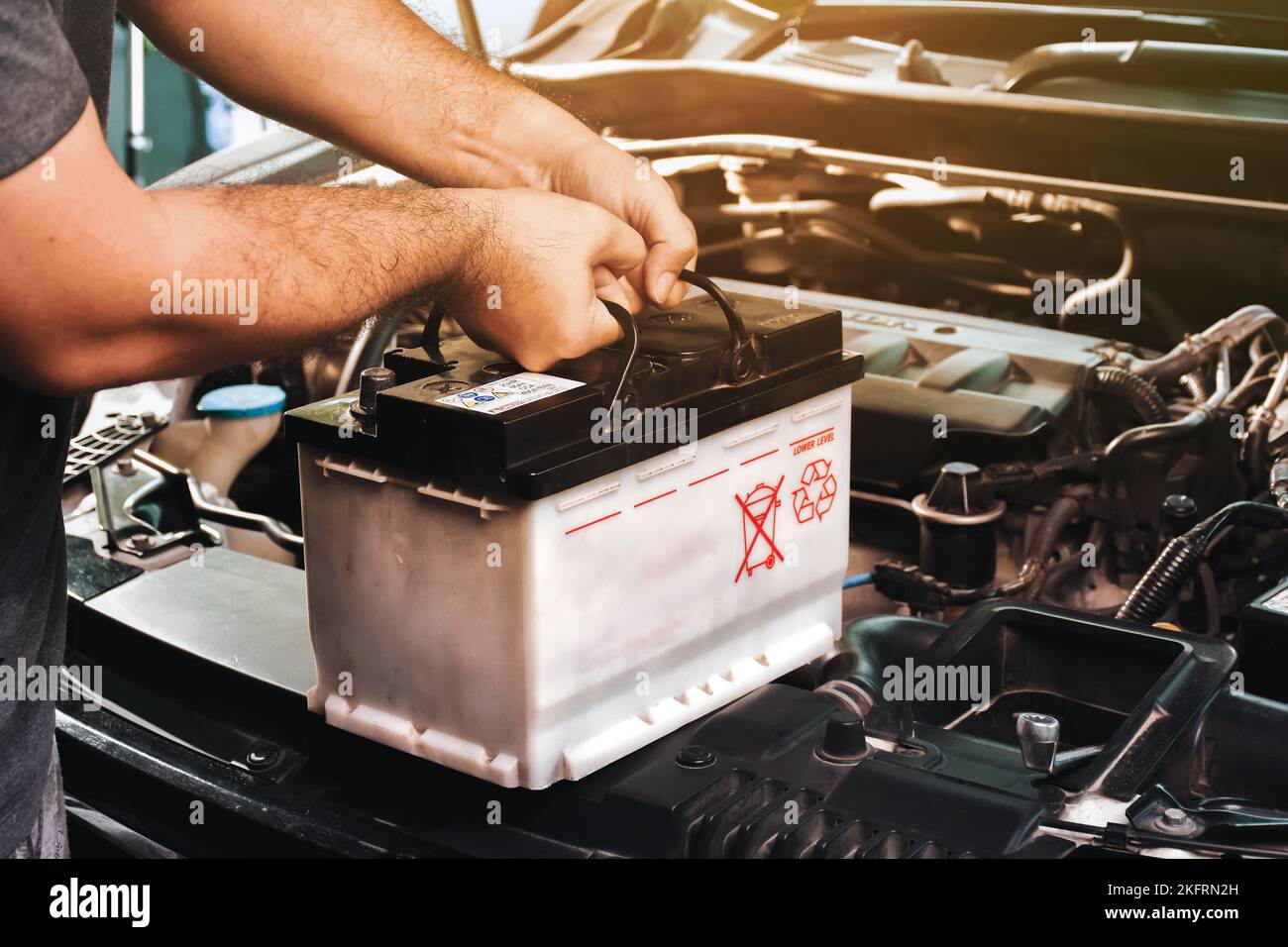 Ein Automechaniker trägt eine Ersatz-Autobatterie für die elektrische Instandhaltung von Autos Stockfoto