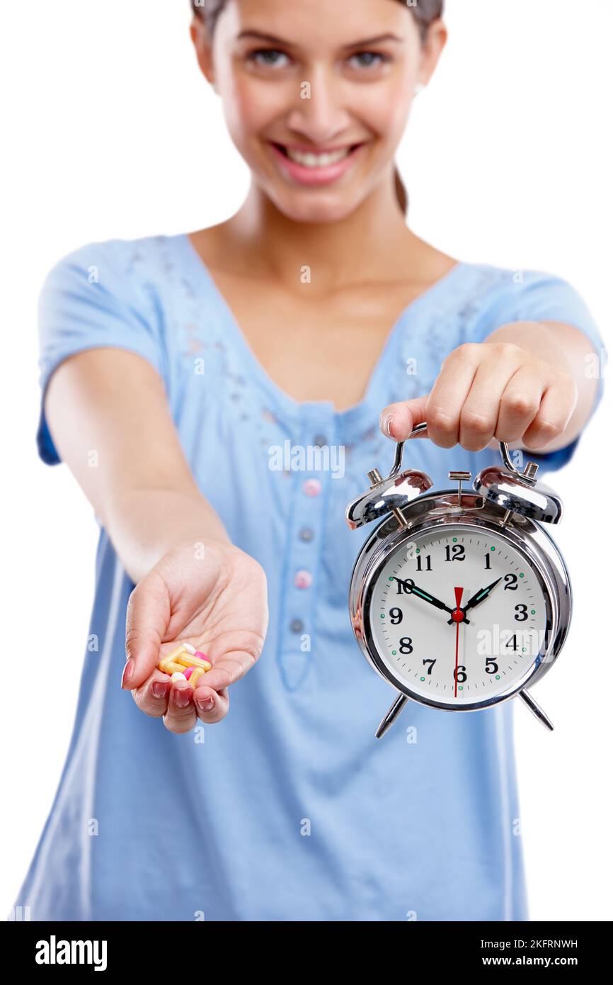 Drehen Sie die Uhr mit den täglichen Vitaminen zurück. Studioporträt einer jungen Frau mit einer Handvoll Tablets und einer Uhr. Stockfoto