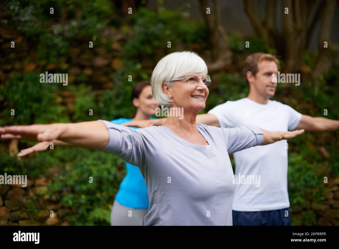 Nie zu alt, um Neues zu lernen. Eine ältere Frau genießt einen Yoga-Kurs im Freien. Stockfoto