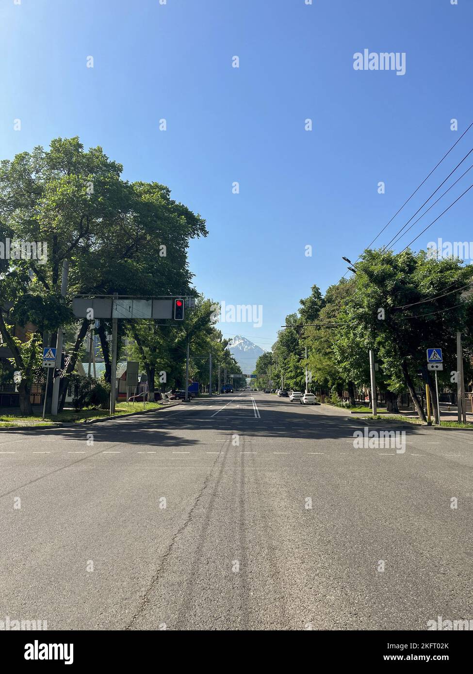 Kreuzung auf der Straße in der Stadt am Horizont mit Bergen. Stockfoto